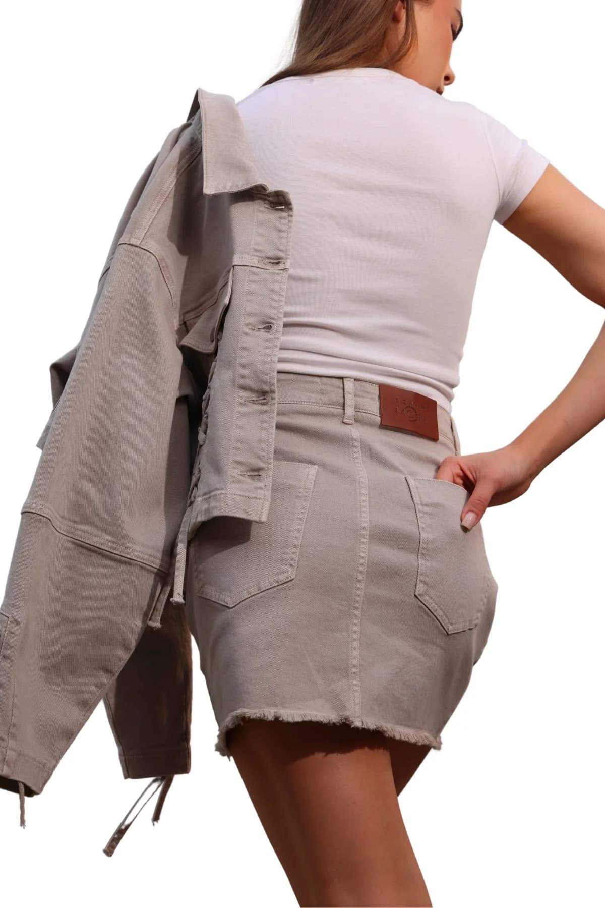 Denim Moon kadın taş rengi denim mini etek, arka cep ve deri bel etiketi detayı, modelde arkadan yakın görünüm.