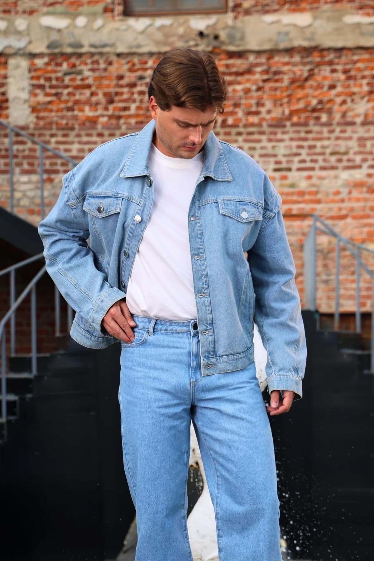 Denim Moon erkek açık mavi oversize denim ceket, modelde eli belde başı öne eğik önden görünüm.